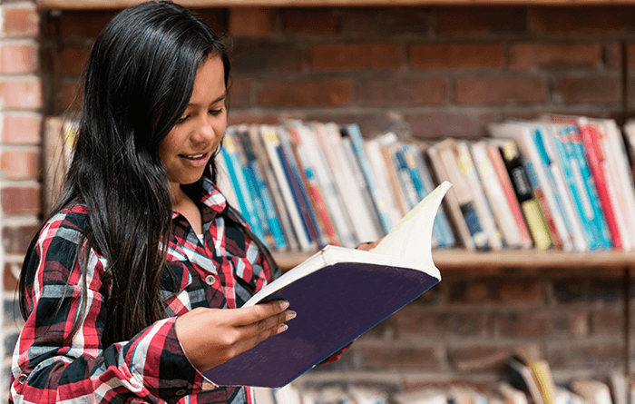 Young female student in the library reading a book.
